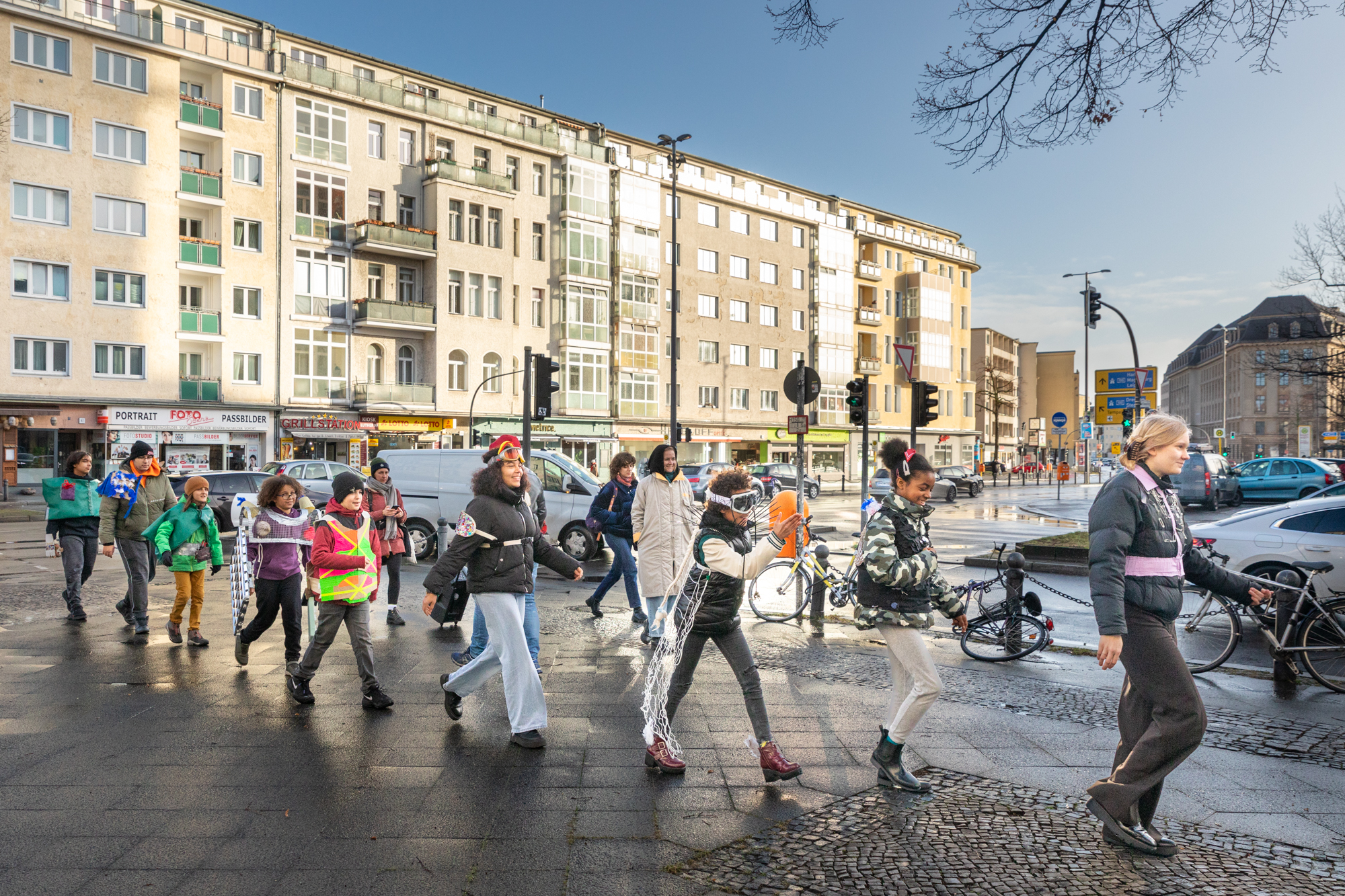 9 Personen auf der Straße unterwegs, zum Teil mit Kostümen.