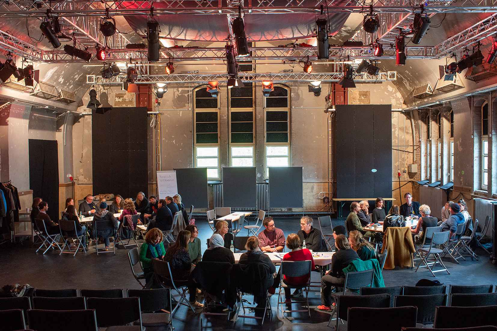 Eine Gruppe von Menschen sitzt im Stuhlkreis auf der Bühne